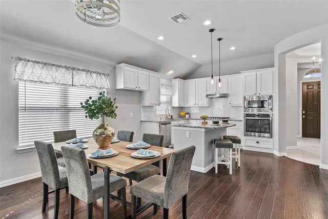 dining area with dark hardwood / wood-style floors, lofted ceiling, and sink