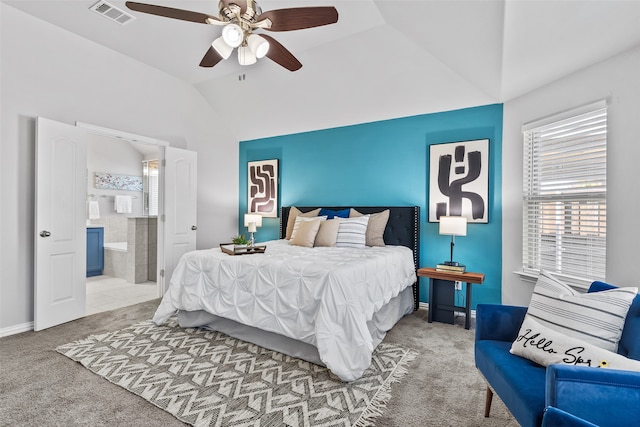 bedroom featuring ceiling fan, vaulted ceiling, light colored carpet, and ensuite bath