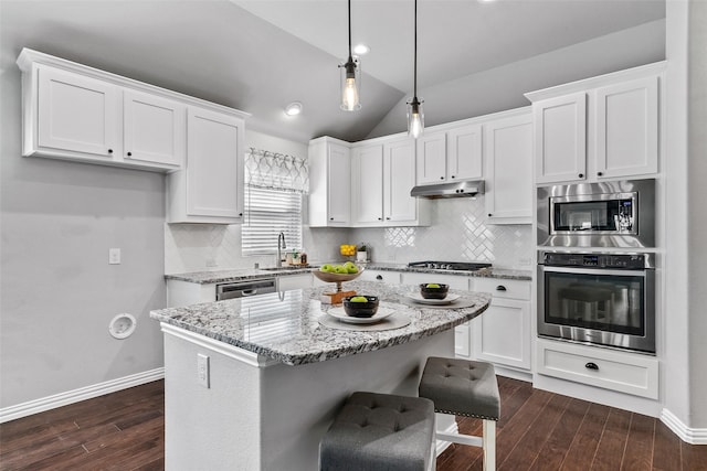 kitchen featuring white cabinets, appliances with stainless steel finishes, light stone countertops, and lofted ceiling