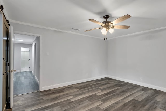 empty room featuring a barn door, ceiling fan, ornamental molding, and dark hardwood / wood-style flooring