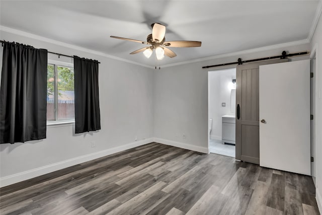 spare room with a barn door, hardwood / wood-style floors, and ceiling fan