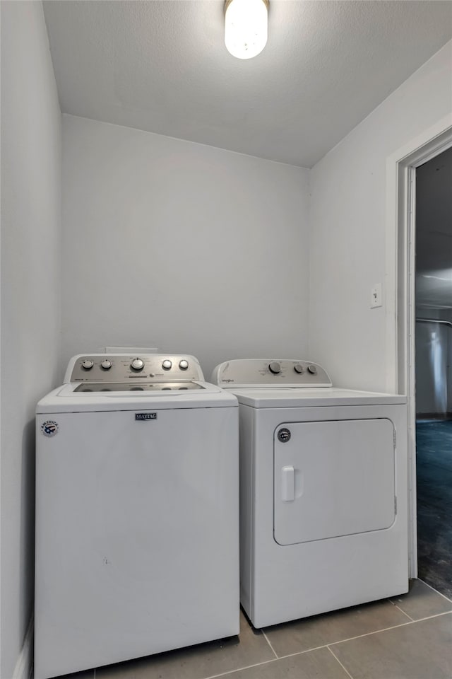 laundry room with a textured ceiling, washing machine and dryer, and light tile patterned floors