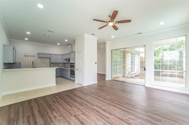 unfurnished living room with light wood-type flooring, ceiling fan, and ornamental molding