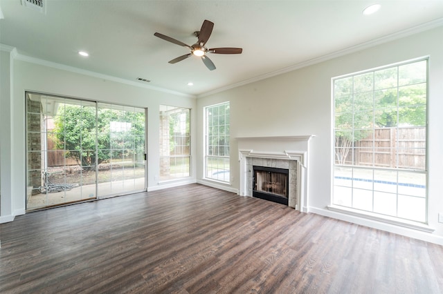 unfurnished living room featuring a healthy amount of sunlight, ceiling fan, a tile fireplace, and dark wood-type flooring