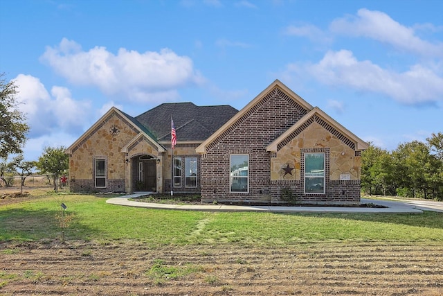 view of front of house featuring stone siding, brick siding, a front yard, and fence