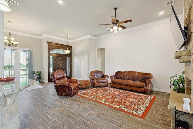 living room with crown molding, dark wood-type flooring, ceiling fan with notable chandelier, and a fireplace