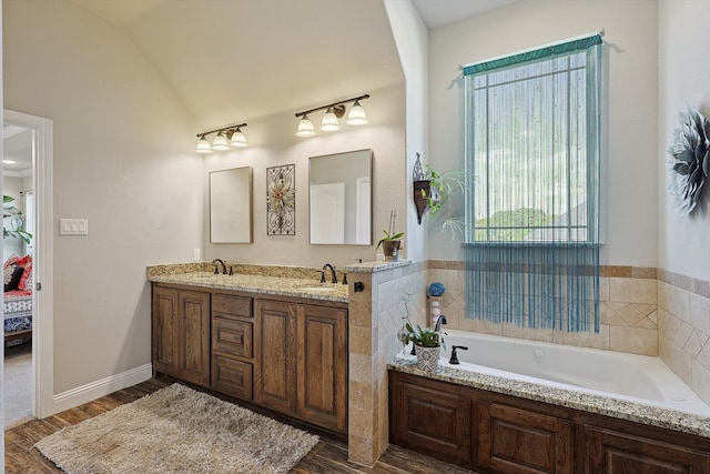 bathroom featuring vanity, lofted ceiling, wood-type flooring, and a washtub