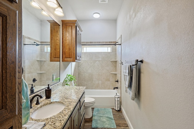 full bathroom with tiled shower / bath, vanity, toilet, and hardwood / wood-style flooring