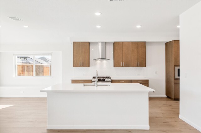 kitchen featuring sink, light hardwood / wood-style flooring, a kitchen island with sink, and stainless steel gas stovetop