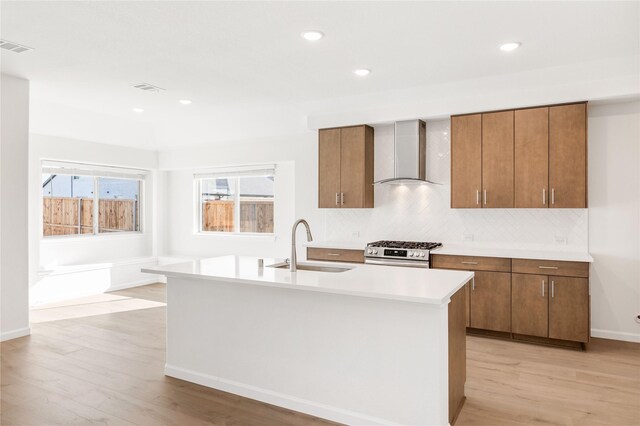 kitchen featuring light hardwood / wood-style floors, tasteful backsplash, wall chimney range hood, and stainless steel appliances