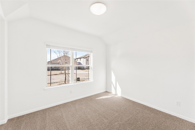 carpeted spare room featuring vaulted ceiling