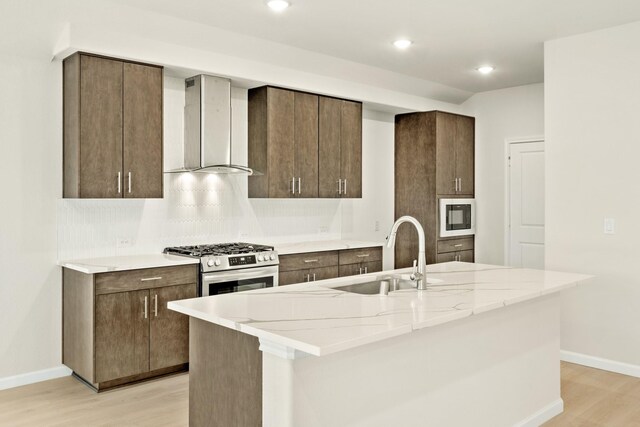 kitchen with hardwood / wood-style floors, stainless steel appliances, sink, ceiling fan, and a kitchen island with sink