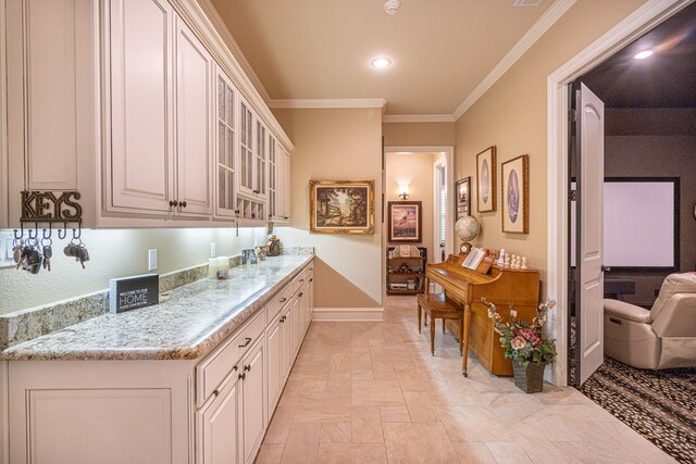 interior space featuring white cabinets, light stone counters, and crown molding