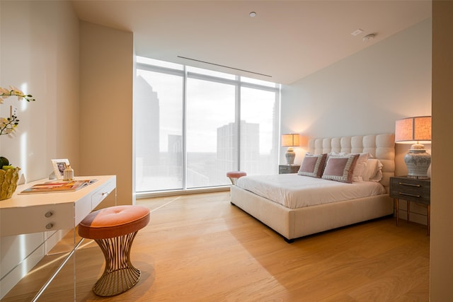 bedroom with light hardwood / wood-style flooring and a wall of windows