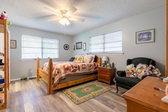 bedroom with ceiling fan, light hardwood / wood-style floors, and a textured ceiling