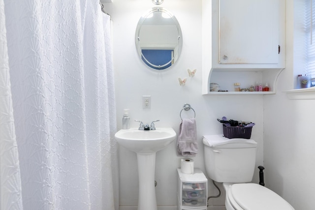 full bath with curtained shower, a sink, and toilet