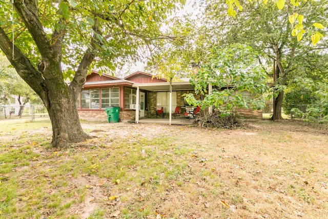 view of front of house with a patio area, a front lawn, fence, brick siding, and a sunroom