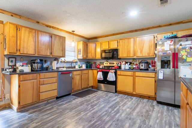 kitchen with crown molding, appliances with stainless steel finishes, a textured ceiling, and hardwood / wood-style flooring