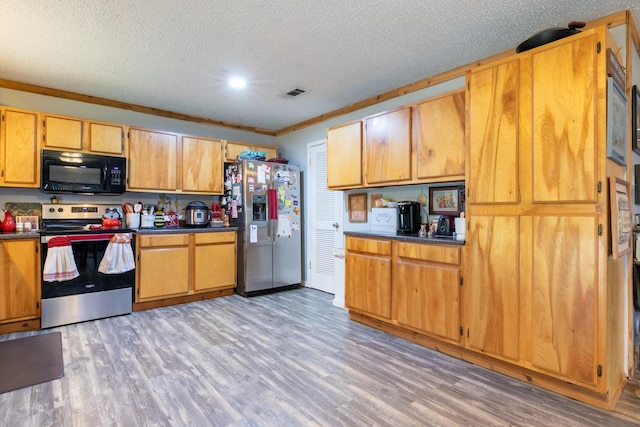 kitchen featuring stainless steel appliances, dark countertops, visible vents, ornamental molding, and light wood-style floors