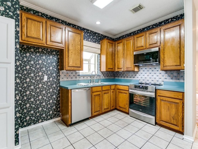 1216 Wooded Trl, Hurst, TX 76053 - kitchen with stainless steel appliances, wallpapered walls, a sink, crown molding, and brown cabinetry