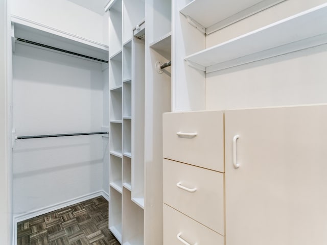 spacious closet with dark parquet flooring