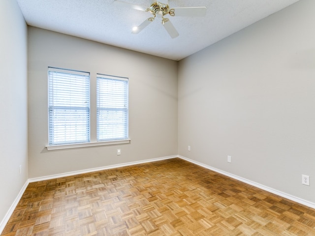 empty room with ceiling fan, a textured ceiling, and light parquet floors