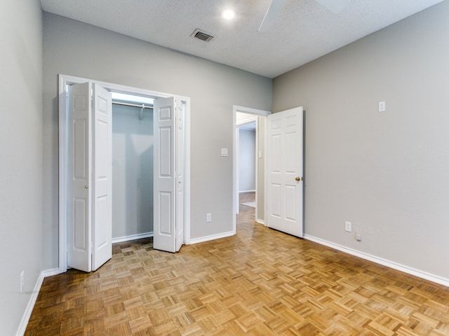 unfurnished bedroom with ceiling fan, light parquet flooring, and a textured ceiling