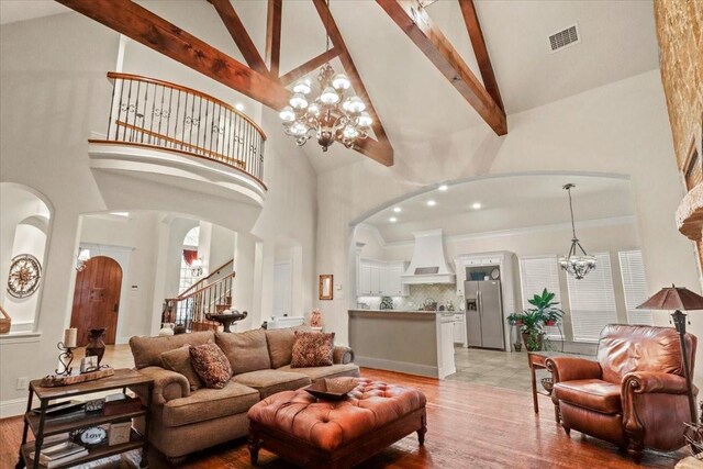 living room with light hardwood / wood-style flooring, high vaulted ceiling, and a chandelier