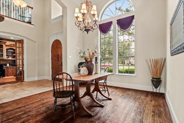 tiled dining space with a high ceiling and an inviting chandelier