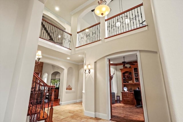 entrance foyer with ceiling fan, a high ceiling, and ornamental molding