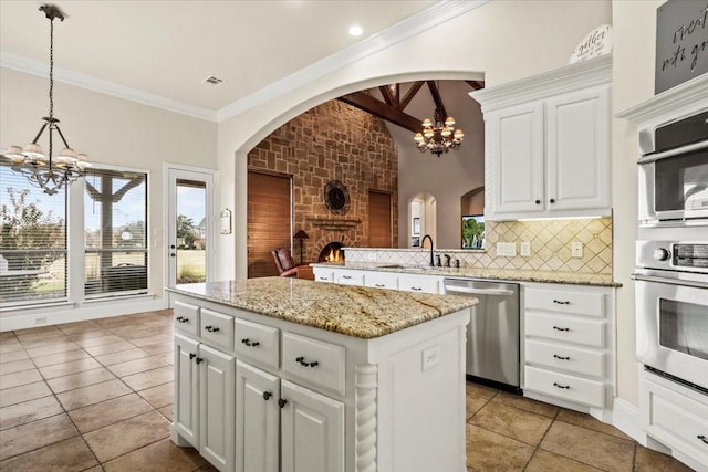 kitchen with stainless steel dishwasher, a kitchen island, white cabinets, and pendant lighting