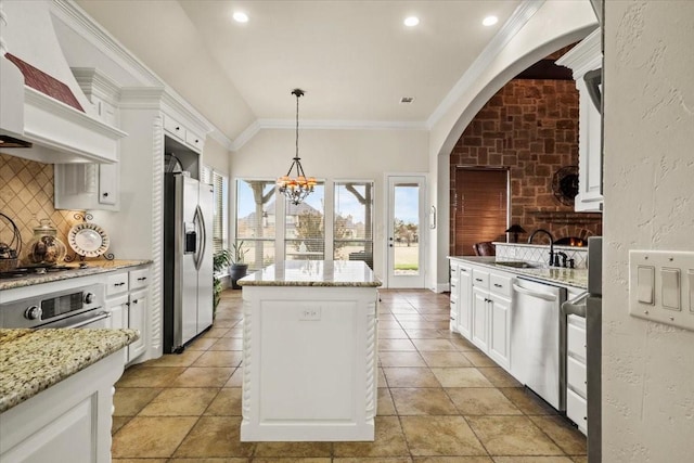 kitchen with pendant lighting, sink, light stone countertops, appliances with stainless steel finishes, and a kitchen island