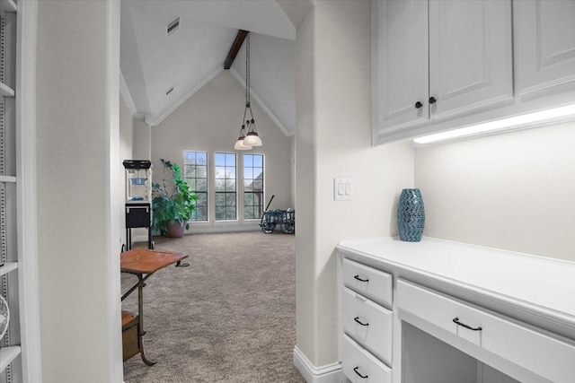 interior space featuring lofted ceiling, light carpet, white cabinets, and decorative light fixtures