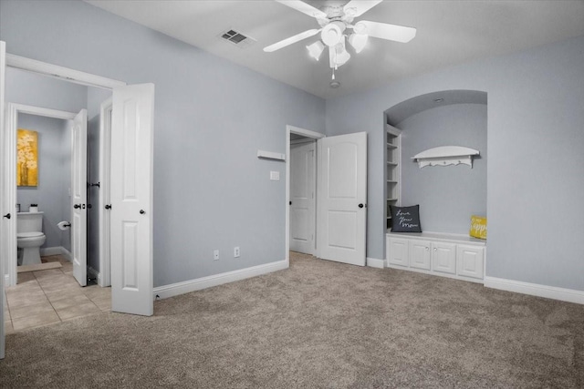 unfurnished bedroom with connected bathroom, light colored carpet, and ceiling fan