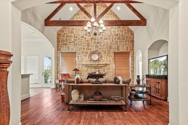 living room with beam ceiling, wood-type flooring, high vaulted ceiling, a notable chandelier, and a fireplace