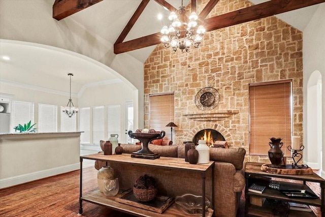 living room featuring high vaulted ceiling, a stone fireplace, beamed ceiling, a notable chandelier, and wood-type flooring