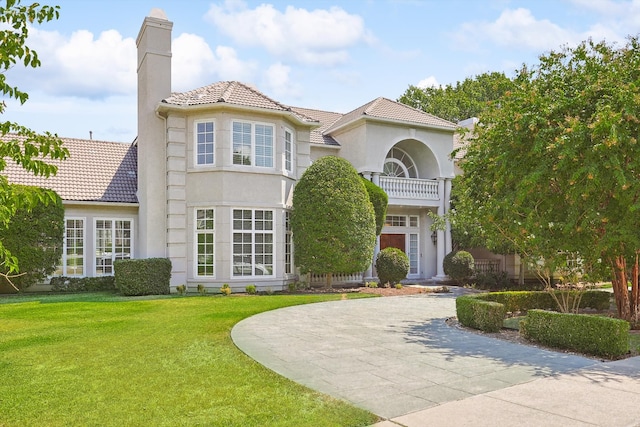 mediterranean / spanish-style house featuring a balcony and a front yard