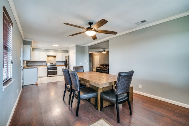 dining area featuring light wood-type flooring, crown molding, sink, and ceiling fan