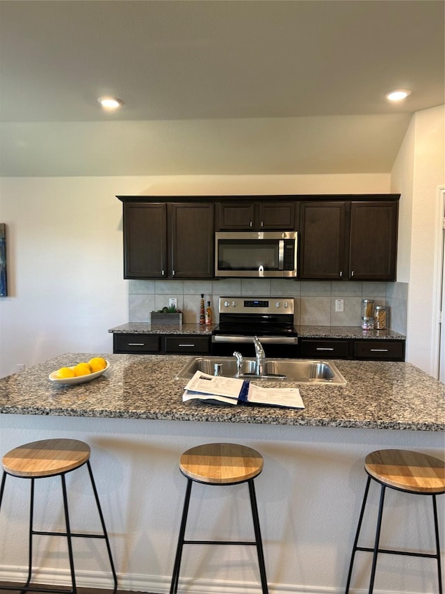 kitchen with backsplash, a kitchen bar, and appliances with stainless steel finishes