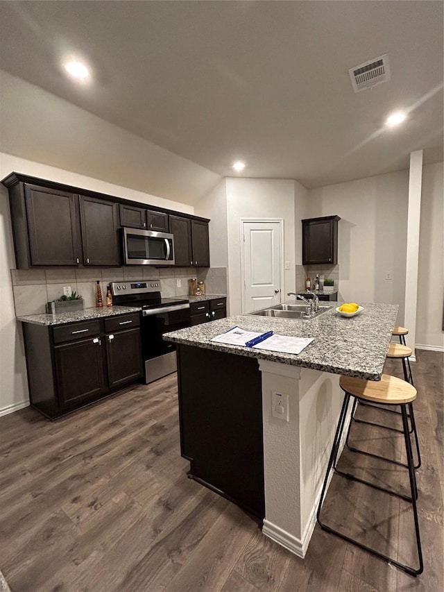 kitchen featuring dark hardwood / wood-style flooring, sink, stainless steel appliances, and a kitchen island with sink