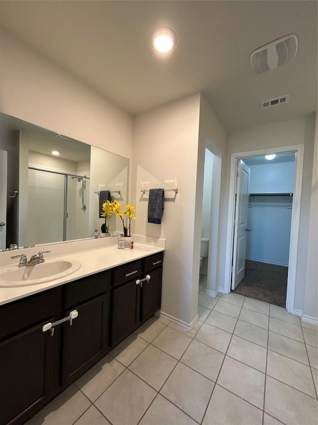 bathroom with tile patterned floors, vanity, toilet, and a shower with shower door