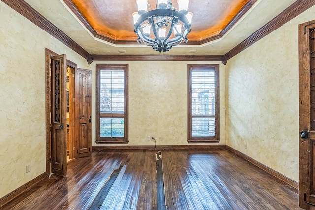 unfurnished room with crown molding, dark wood-type flooring, a tray ceiling, and a chandelier