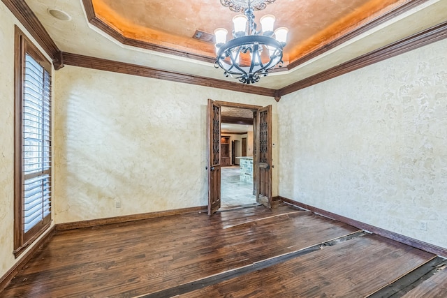 empty room featuring a chandelier, a wealth of natural light, dark hardwood / wood-style flooring, and ornamental molding