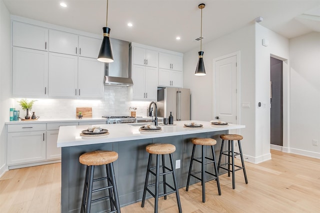 kitchen with a center island with sink, light hardwood / wood-style flooring, appliances with stainless steel finishes, and white cabinets