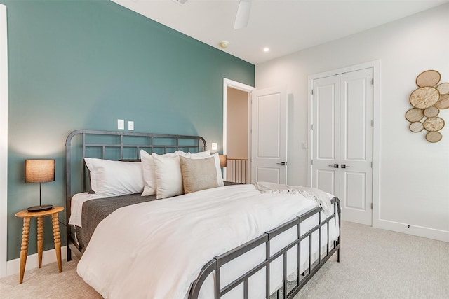 bedroom featuring light colored carpet, ceiling fan, and a closet