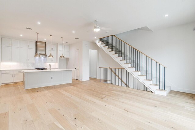 unfurnished living room with light hardwood / wood-style flooring, ceiling fan, and sink