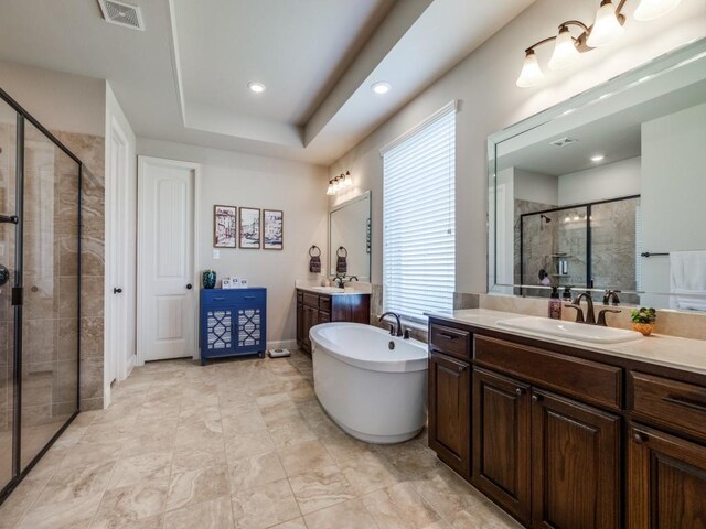 bathroom with vanity, a tray ceiling, and separate shower and tub