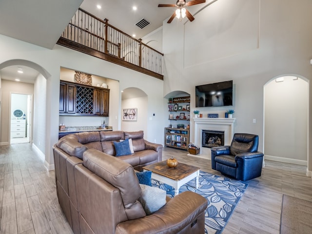 living room featuring a high ceiling, light wood-type flooring, and ceiling fan