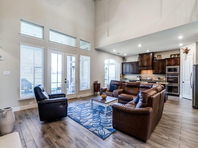 kitchen featuring an island with sink, stainless steel appliances, light stone countertops, dark brown cabinetry, and light hardwood / wood-style floors