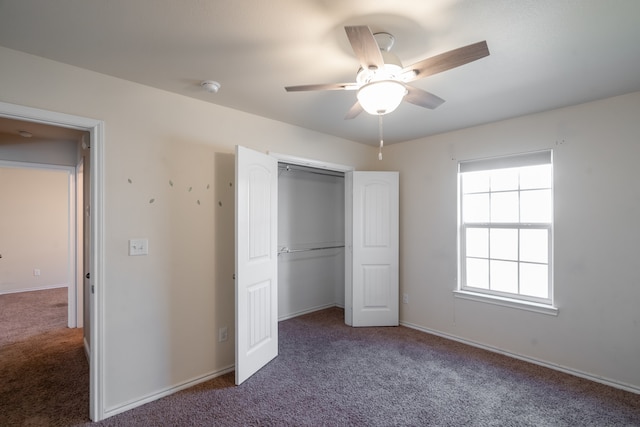 unfurnished bedroom featuring dark colored carpet, a closet, and ceiling fan